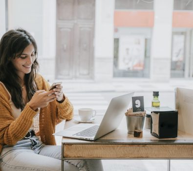 cheerful-woman-browsing-smartphone-cafe